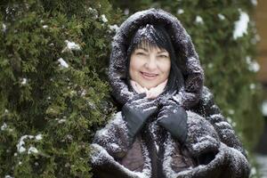 anziano donna nel un' pelliccia cappuccio coperto con neve foto