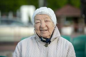 anziano donna con rughe nel un' a maglia cappello, sorridente, guardare a il telecamera. un Ottanta cinque anno vecchio donna. foto