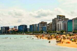 un' spiaggia con molti persone su esso e edifici nel il sfondo foto