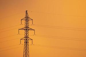 pilone di trasmissione di elettricità contro il cielo arancione foto