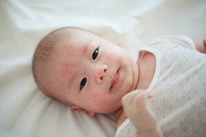 felicità nel innocenza asiatico bambino ragazzo sorrisi su accogliente letto foto