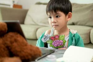 asiatico ragazzo studiando in linea e fare attività su il computer portatile foto