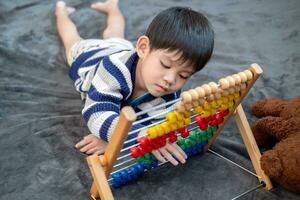 asiatico ragazzo giocando con giocattoli su il letto foto