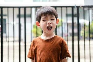 contento viso di asiatico ragazzo mangiare cioccolato caramella foto