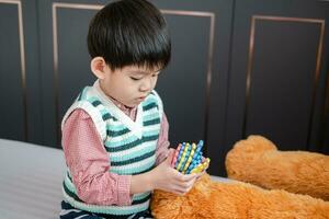 asiatico ragazzo giocando con sega puzzle su il letto con gioia foto