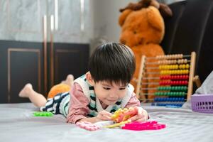 asiatico ragazzo giocando con sega puzzle su il letto con gioia foto