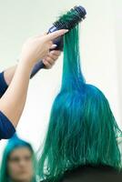parrucchiere pettini e si asciuga capelli di Smeraldo colore con asciugacapelli dopo tintura capelli radici nel colore di lapis lazuli foto