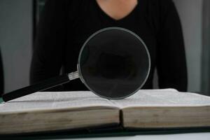 ingrandimento bicchiere al di sopra di Aperto libro su tavolo. formazione scolastica e ricerca concetto. foto