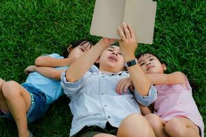 contento madre e Due figlie avendo divertimento e godendo lettura a il parco. madre e figlia riposo nel il estate giardino, lei legge Fata racconti per sua figlia. foto