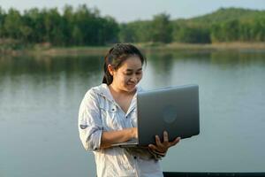 femmina ambientalista utilizzando il computer portatile computer per disco naturale acqua contaminazione controlli. biologo analizzando acqua test risultati utilizzando tecnologia applicazione su il computer portatile. acqua e ecologia concetto foto