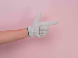 mani nel bianca a maglia guanti isolato su rosa sfondo. femmina mano puntamento con un' cotone guanto. foto