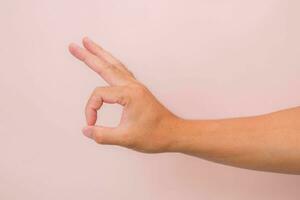 maschio mano mostrando va bene gesto isolato su rosa sfondo. foto
