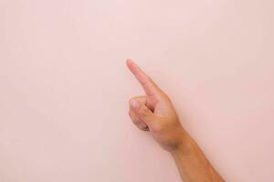 avvicinamento di maschio mano puntamento isolato su rosa sfondo. dell'uomo mano toccante o puntamento per qualcosa foto