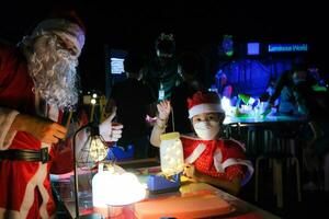 genitori e bambini godere la spesa Natale vigilia insieme, fabbricazione Natale albero decorazioni. carino ragazza giocando con Natale luci foto