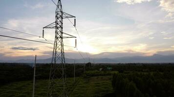 aereo Visualizza di alto voltaggio piloni e fili nel il cielo a tramonto nel il campagna. fuco metraggio di elettrico poli e fili a crepuscolo. foto