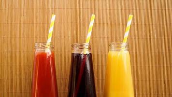 tre bevande multicolori in bottiglia su uno sfondo di bambù in legno foto
