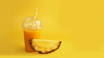 succo d'ananas in un bicchiere di plastica su sfondo giallo foto