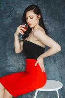 bella giovane donna con un bicchiere di vino su sfondo grigio