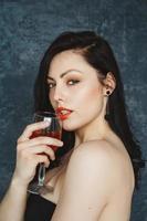 bella giovane donna con un bicchiere di vino su sfondo grigio foto