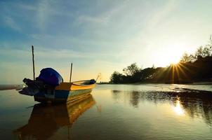 barca vicino alla spiaggia quando il sole tramonta