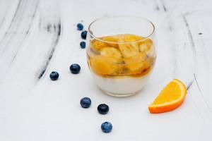 gelatina di frutta colorata in un bicchiere su sfondo bianco con mirtilli