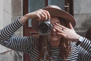 la bella donna con il cappello sta scattando una foto con la macchina fotografica vecchio stile