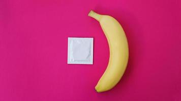 preservativo e banana su sfondo rosa. concetto di sesso foto