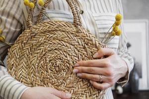 mani di donna con elegante borsa in rattan nudo alla moda e borsa di paglia foto