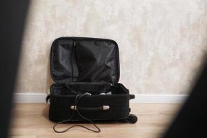 valigia nera vuota aperta per cose diverse su sfondo grigio foto