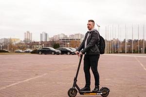 uomo moderno in sella a uno scooter elettrico in città foto