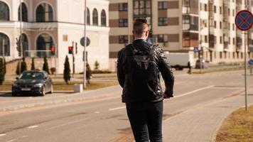 schiena di un uomo con uno zaino nero. un uomo guida uno scooter elettrico foto