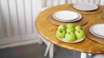 mele verdi su un piatto bianco su un tavolo di legno