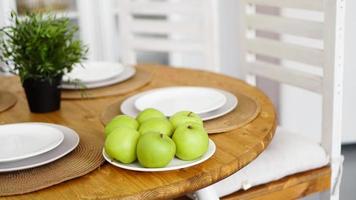 mele verdi su un piatto bianco su un tavolo di legno
