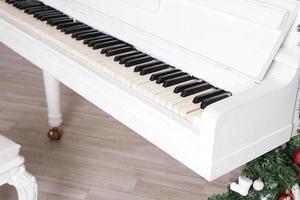 tasti su pianoforte verticale bianco con decorazioni natalizie foto