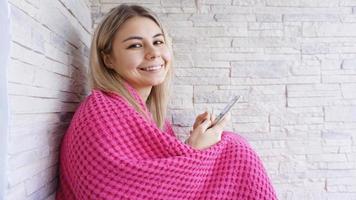 bella ragazza seduta sul davanzale della finestra con lo smartphone in mano. foto