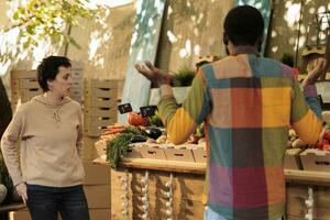 femmina vegetariano shopping a Locale agricoltori mercato per acquistare naturale eco produrre. cliente mettendo fresco biologico di stagione frutta e verdure nel cartone scatola, acquisto salutare di produzione locale prodotti. foto