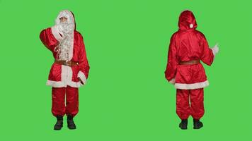 Santa dà pollici su e pollici giù al di sopra di schermo verde fondale nel studio, indossare santo nick costume. giovane persona raffigurante inverno principale carattere, piace e antipatia gesto. foto