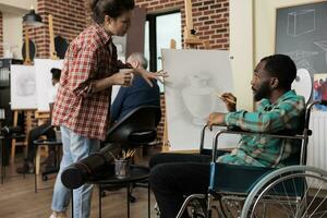 africano americano Disabilitato tipo parlando con insegnante durante gruppo disegno classe, miglioramento sociale abilità attraverso collaborativo opera d'arte. insegnamento arte per persone con disabilità foto