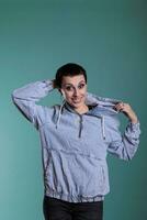 sorridente allegro donna giocando con cappuccio mentre in posa divertente nel studio al di sopra di isolato sfondo. fiducioso bellissima con di moda trucco guardare a telecamera fabbricazione carino espressione foto