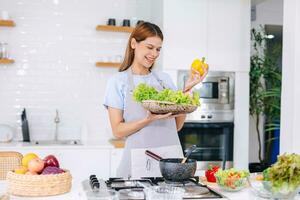 contento giovane donna fabbricazione insalata. persone mangiare salutare cibo. vegano signora nel cucina casa. mangiare verdura per stare a dieta. preparare dieta pasto a isola fornello. foto