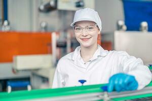 contento adolescente giovane donne lavoratore nel trasportatore cintura produzione linea nel cibo e bevanda fabbrica con dipendente bianca igiene Abiti foto