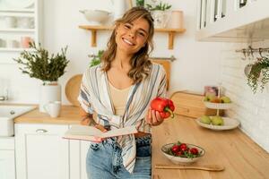 bella ragazza guardare a ricetta nel cucina libro preparazione verdura insalata cucinando cibo nel leggero cucina a casa. dieta salutare stile di vita concetto. foto