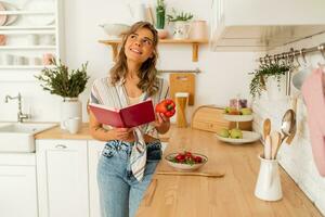 bella ragazza guardare a ricetta nel cucina libro preparazione verdura insalata cucinando cibo nel leggero cucina a casa. dieta salutare stile di vita concetto. foto