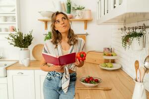 bella ragazza guardare a ricetta nel cucina libro preparazione verdura insalata cucinando cibo nel leggero cucina a casa. dieta salutare stile di vita concetto. foto