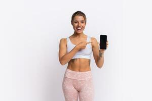 formazione app. in forma bella donna mostrando smartphone con moderno fitness applicazione per puntamento gli sport attività. in posa al di sopra di giallo studio sfondo. foto