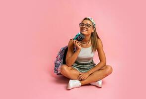 sorridente biondo donna nel bianca superiore e pantaloncini in posa con telecamera su rosa sfondo. estate stile di vita. viaggio concetto. foto