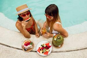 carino beato amici godendo gustoso vegano cibo nel piscina durante tropicale vacanza nel bali. piatto di esotico frutta. festa umore. foto