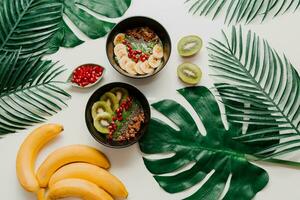 acai ciotola con salutare frutti di bosco, kiwi, avocado su tropicale palma foglia su bianca sfondo. salutare vegetariano cibo. foto
