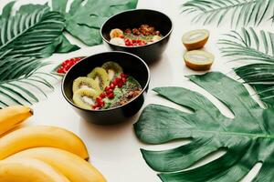 acai ciotola con salutare frutti di bosco, kiwi, avocado su tropicale palma foglia su bianca sfondo. salutare vegetariano cibo. foto