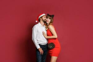 elegante coppia nel amore in posa su rosso sfondo nel alla moda elegante vestito. nuovo anno umore foto